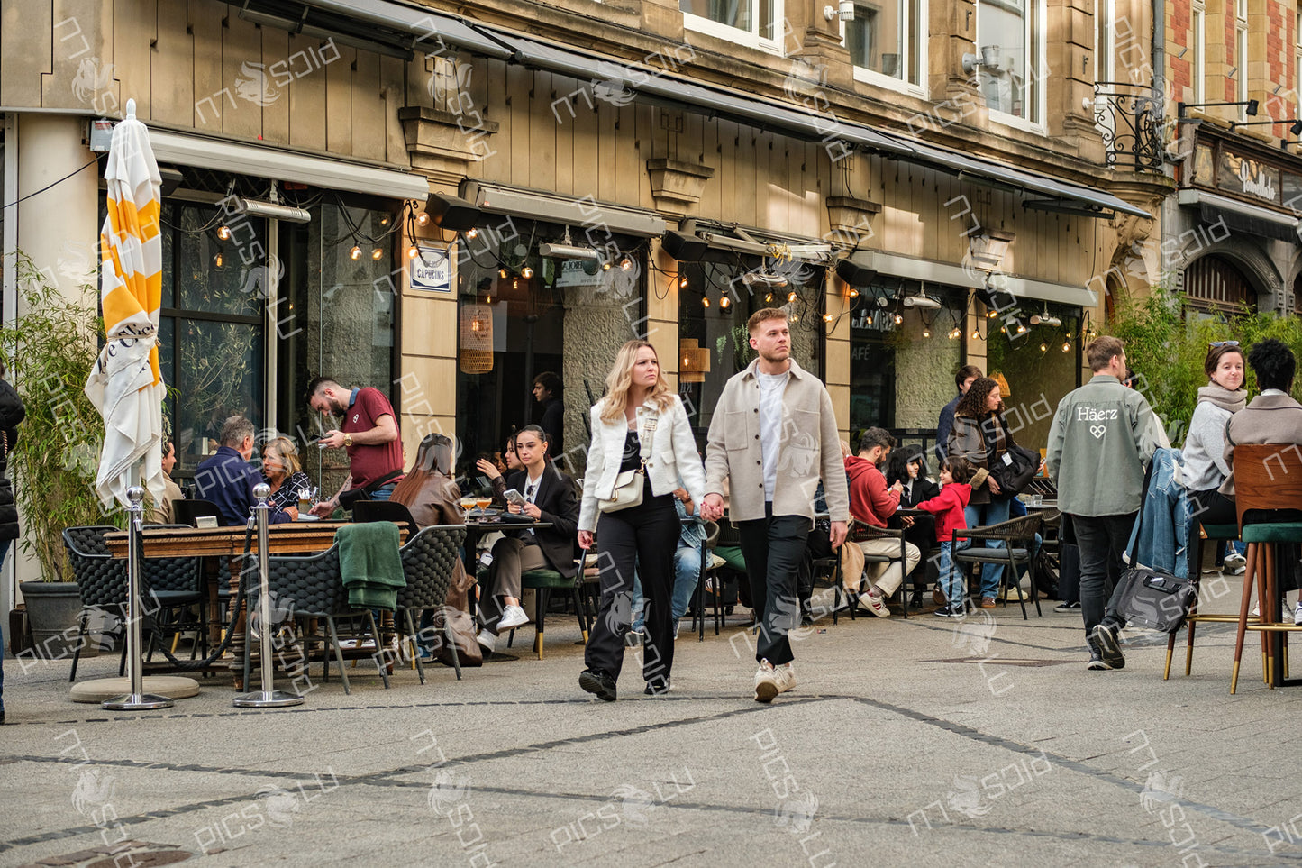 Couple walking past busy terrace café in Luxembourg city