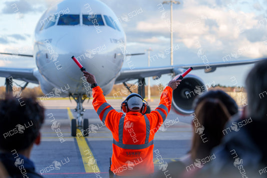 Ground crew guides Luxair aircraft at Luxembourg Airport