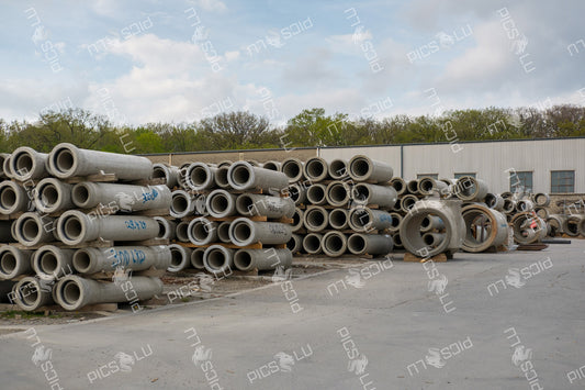 Stacked concrete pipes at a construction storage site in Sandweiler