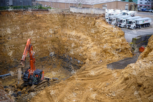 Excavator breaking rock at a deep construction site in Luxembourg