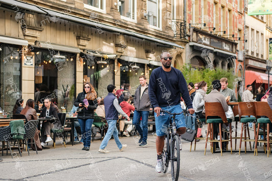 Bicyclist passing by busy café street in Luxembourg city