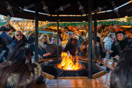 People warming up around an open fire pit at a cozy Christmas market in Luxembourg