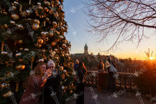 Tourists taking a selfie near a Christmas tree with a view of the Luxembourg skyline