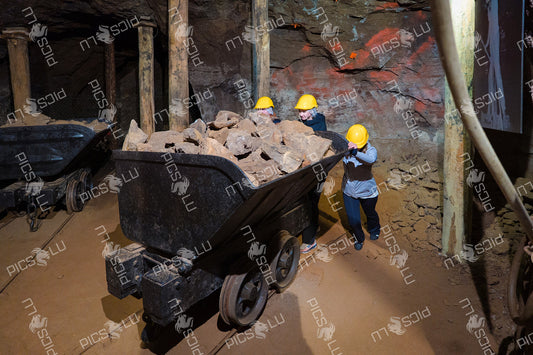 Visitors pushing a mine cart filled with rocks inside a historical mining tunnel