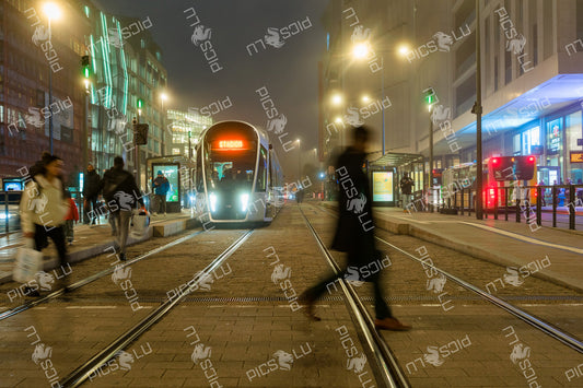 People Crossing in Front of Night Tram